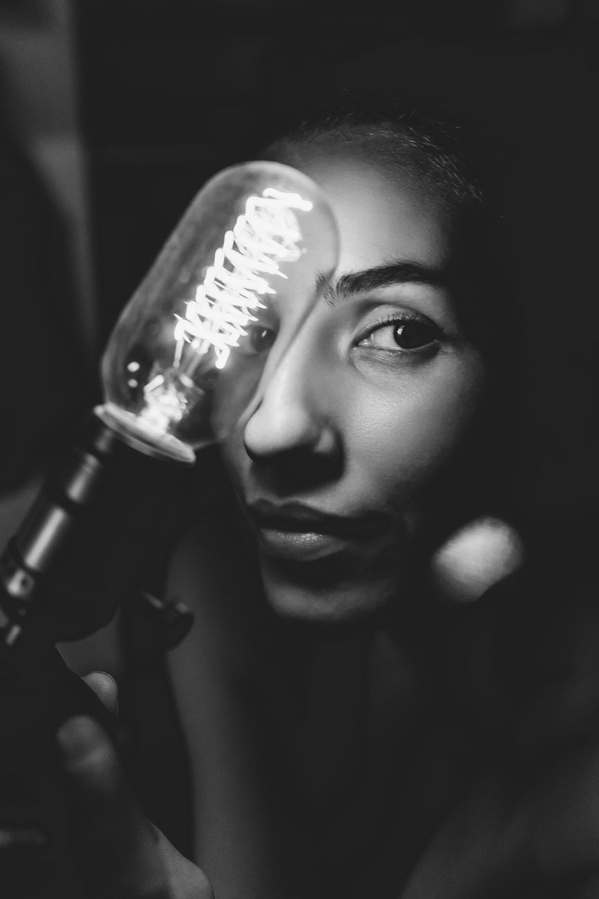grayscale photography of a woman holding a light bulb