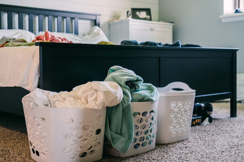 baskets with laundry standing on the floor by the bed