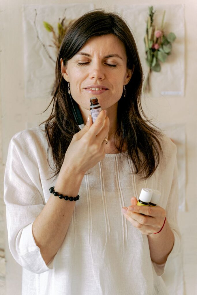woman in white top smelling essential oil