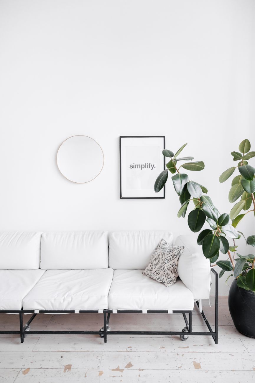 Minimalistischer Einrichtungsstil, weiße Couch mit Pflanze und Bild