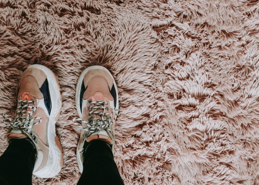 a person wearing rubber shoes standing on a carpet